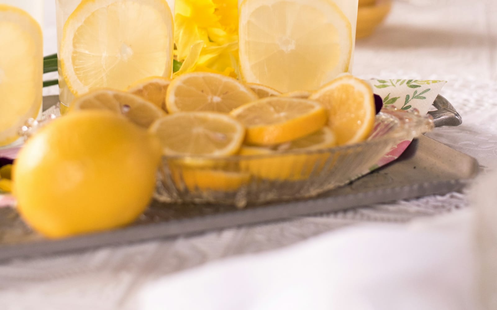 Sliced lemons on a tray beside two glasses of water